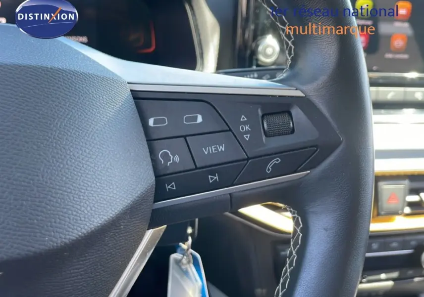 Gros plan sur le volant cuir noir avec commandes multifonctions du SEAT Arona gris Magnetic Metal, intérieur moderne.