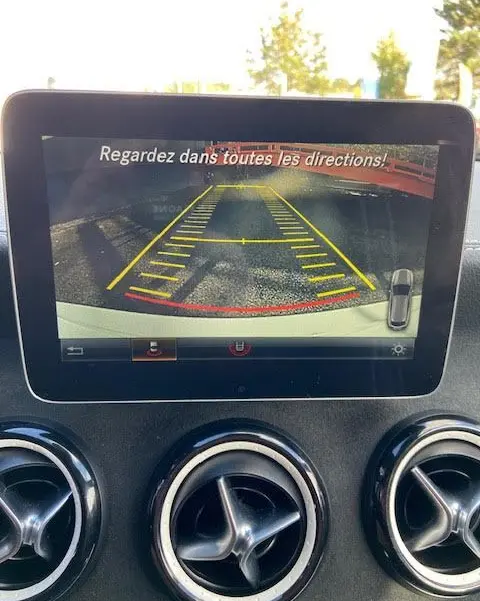Écran de caméra de recul dans une Mercedes CLA Shooting Brake 200D WhiteArt Edition, affichant les lignes de guidage jaunes et rouges.
