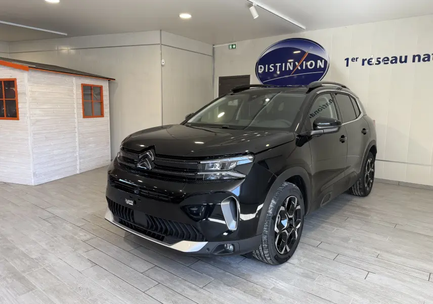 Vue 3/4 avant droit d'un Citroën C5 Aircross noir brillant avec jantes noires et détails chromés en showroom.