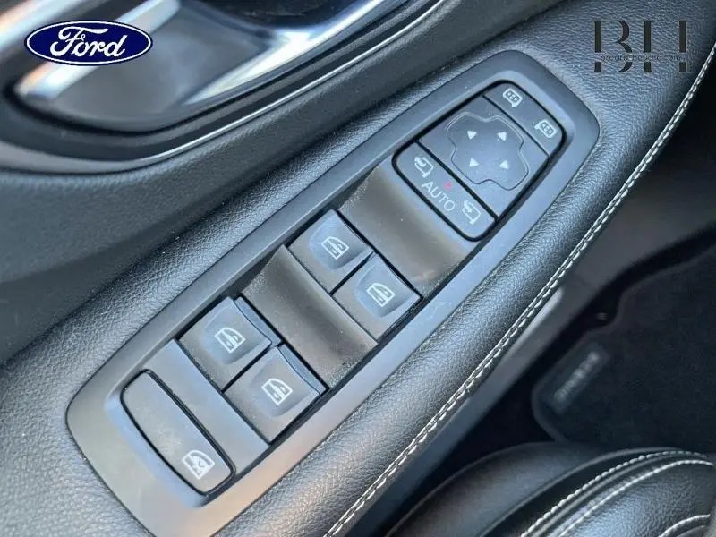 Gros plan sur les commandes des vitres électriques et rétroviseurs sur la porte côté gauche du Renault Scénic blanc nacré 2017.