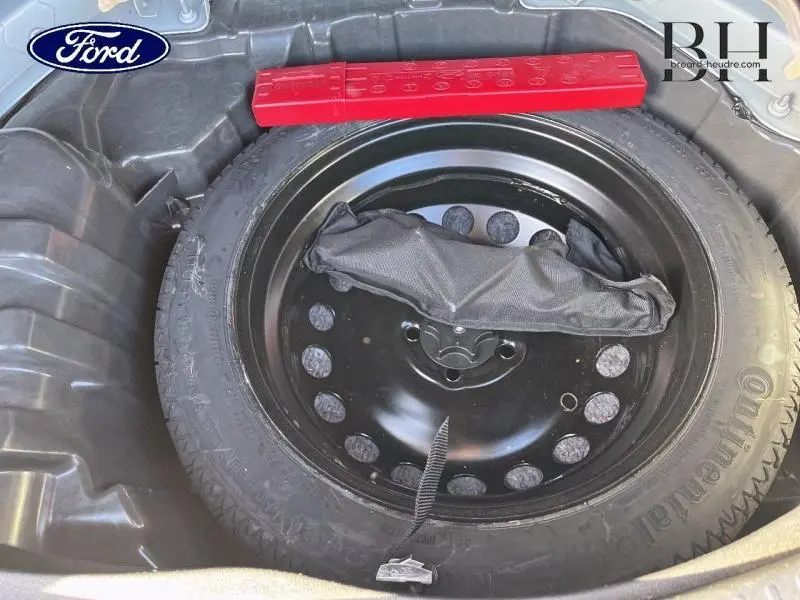 Gros plan sur la roue de secours noire dans le coffre d'un Renault Scenic blanc nacré/noir étoilé de 2017