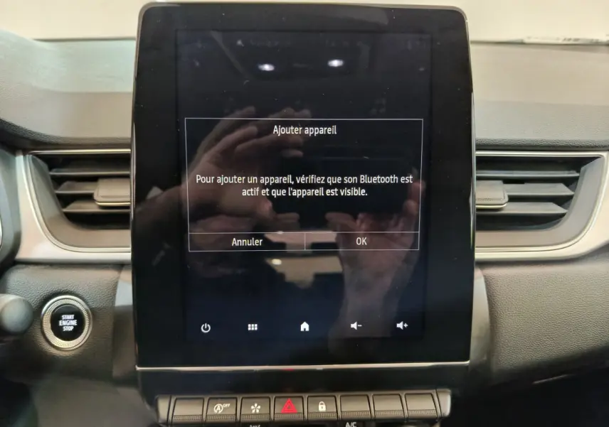 Écran tactile central allumé avec message Bluetooth, tableau de bord gris foncé du Renault Captur 2024 vue de face.