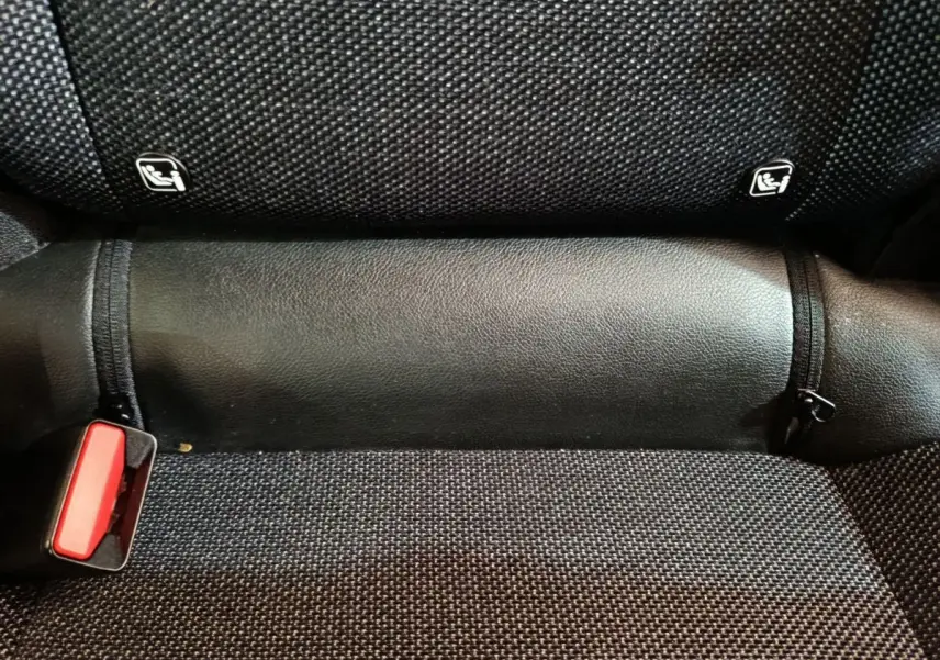 Gros plan sur la banquette arrière noire du Renault Captur 2024, montrant les fixations Isofix et la boucle de ceinture rouge.