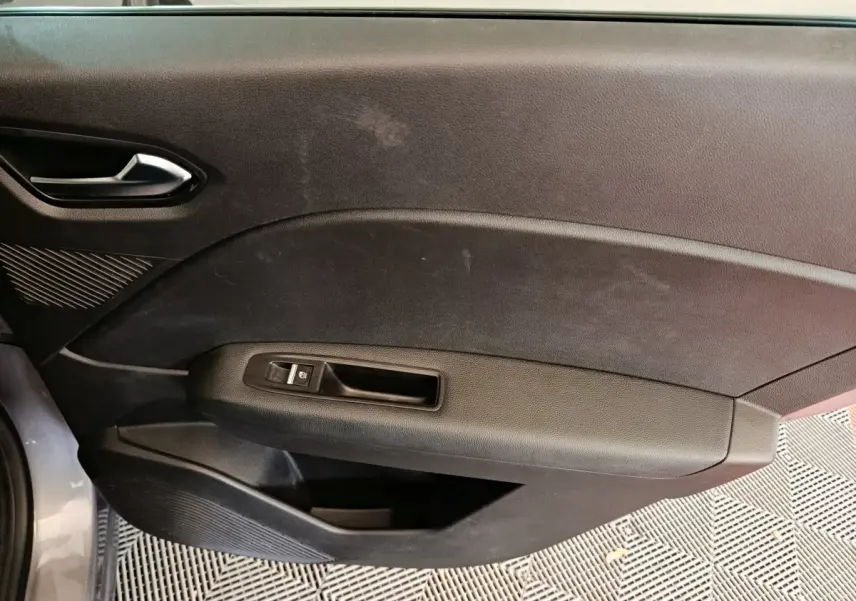 Vue rapprochée de la porte intérieure côté gauche du Renault Captur gris foncé, montrant la poignée et le bouton de vitre électrique.