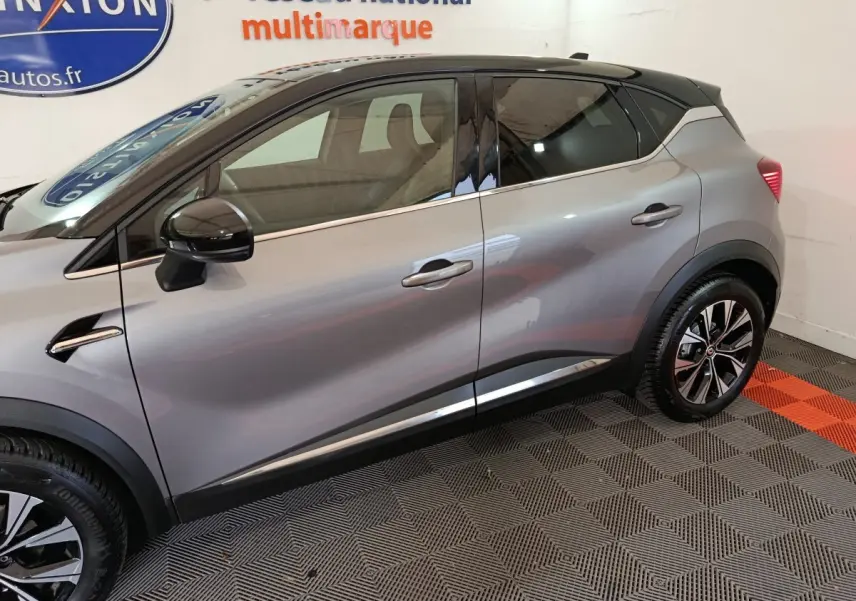 Vue latérale droite d’un Renault Captur 2024 gris foncé avec toit noir et jantes alliage bicolores.