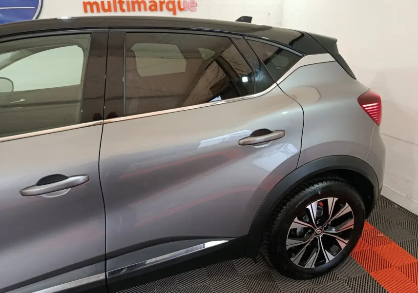 Vue latérale droite du Renault Captur 2024 gris foncé, mettant en valeur la ligne de caisse chromée et les jantes alliage noires.