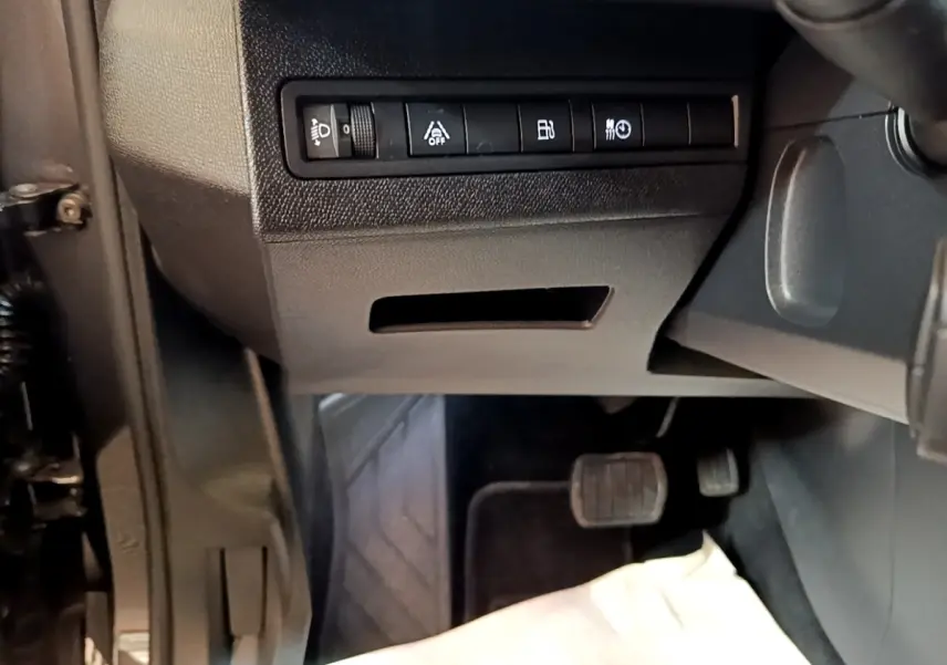 Vue intérieure côté conducteur du Peugeot 3008 gris foncé, montrant les commandes d'assistance et pédales au sol.