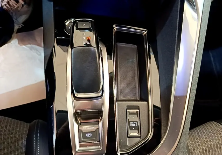 Gros plan sur la console centrale du Peugeot 3008 hybride gris foncé, avec levier de vitesses et bouton Drive Mode.