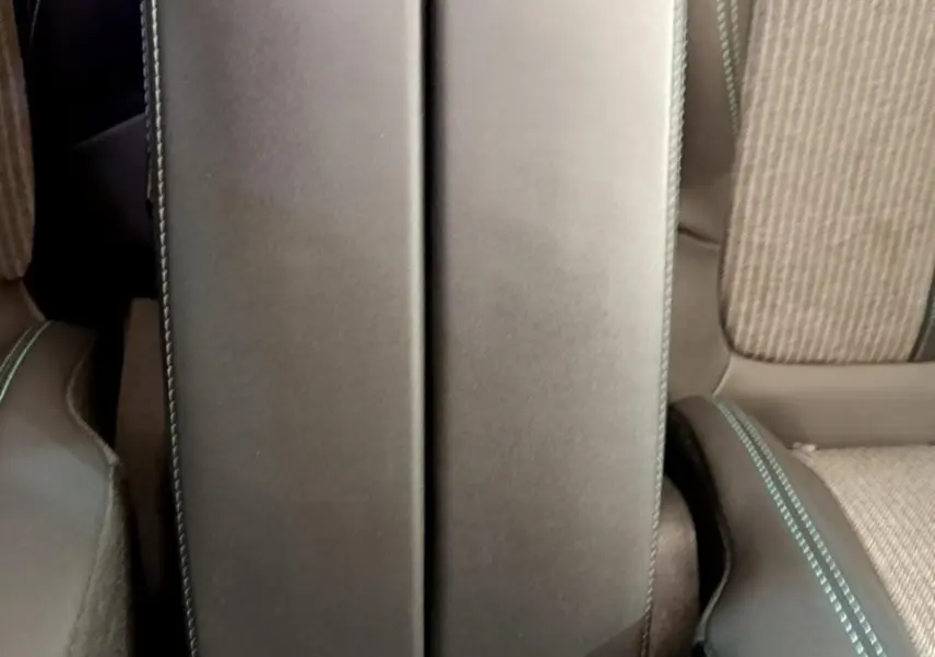 Vue plongeante sur l'accoudoir central noir avec surpiqûres bleues entre les sièges avant du Peugeot 3008 gris foncé.