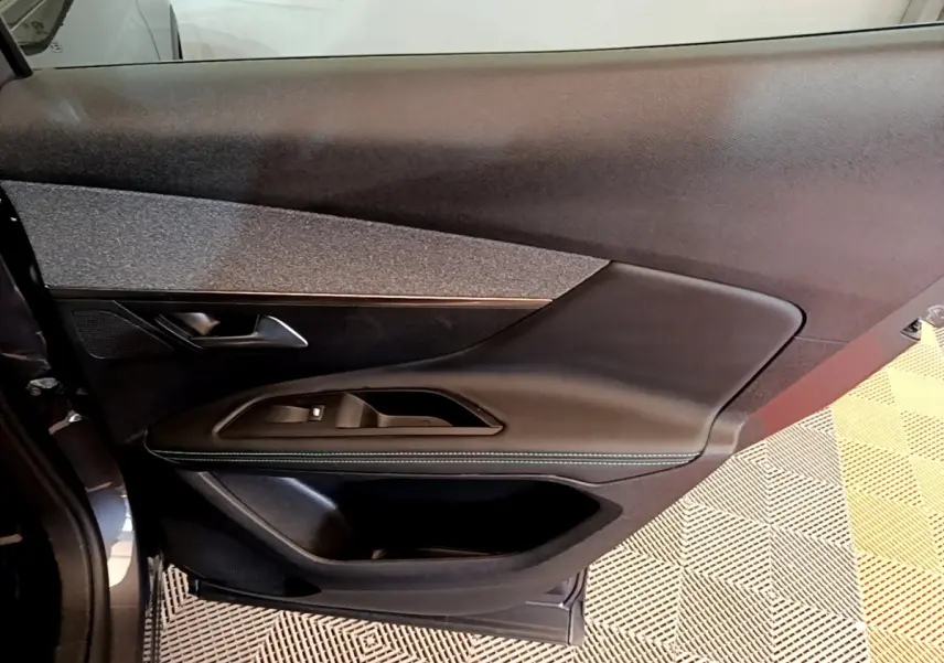 Gros plan sur la porte côté conducteur du Peugeot 3008 gris foncé, montrant les commandes de vitre et le revêtement noir texturé.