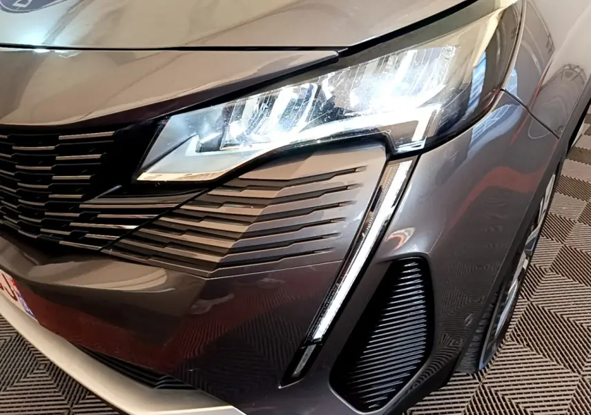 Gros plan sur l'avant droit gris foncé du Peugeot 3008 1.6 HYBRID 225 avec phares LED et calandre distinctive.