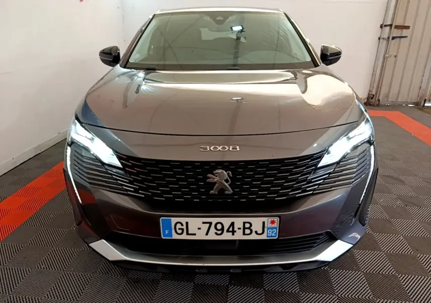 Vue avant d'un Peugeot 3008 gris foncé avec phares LED allumés et calandre noire distinctive.