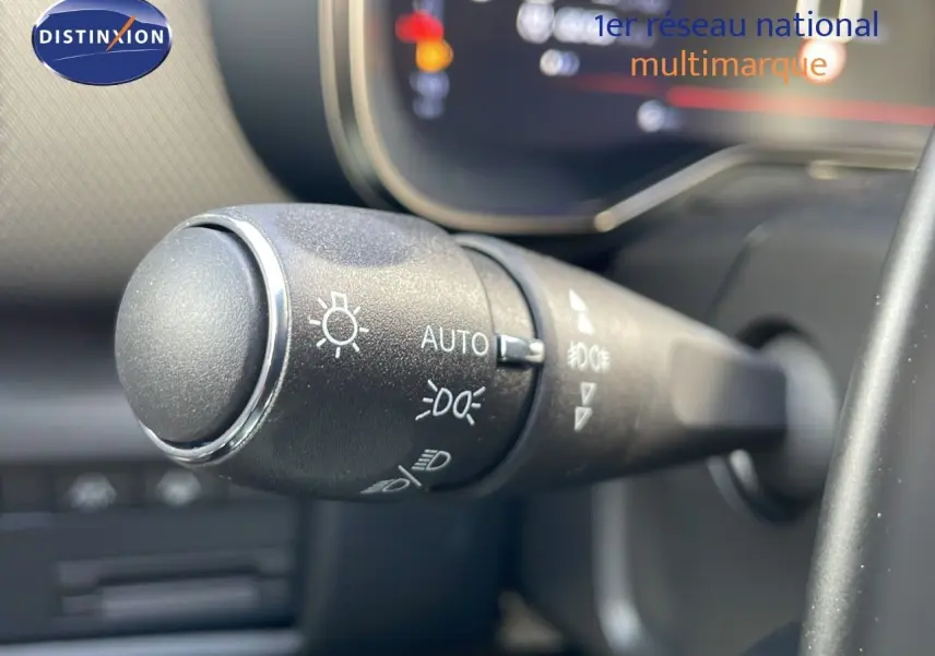 Gros plan sur la commande des phares du Citroën C5 Aircross 2025, intérieur noir avec affichage numérique flou.