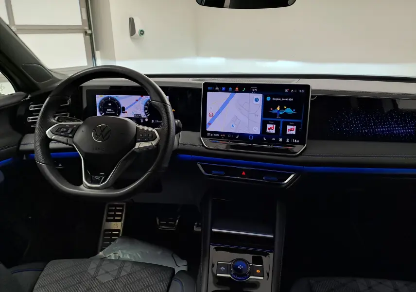 Vue intérieure du tableau de bord du Volkswagen Tiguan 2025 avec écran tactile central et éclairage d'ambiance bleu.