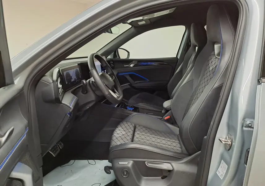 Intérieur avant droit du Volkswagen Tiguan 2.0 TDI 150 DSG7 R-LINE argent Dolomite avec sièges sport noirs et surpiqûres bleues.