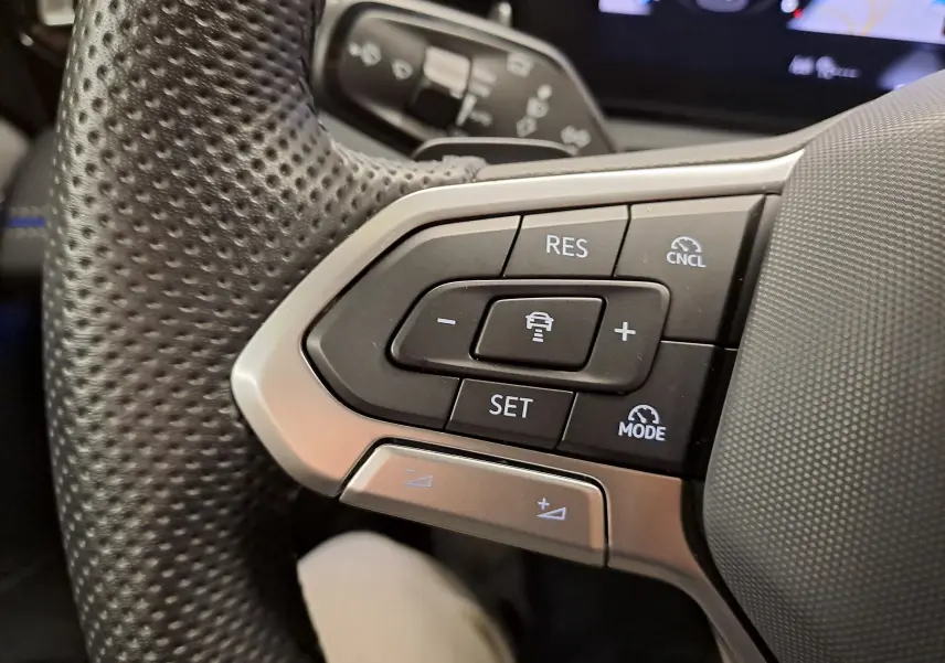 Gros plan sur les commandes du volant en cuir perforé du Volkswagen Tiguan 2.0 TDI 150 DSG7 R-Line, finition noire.