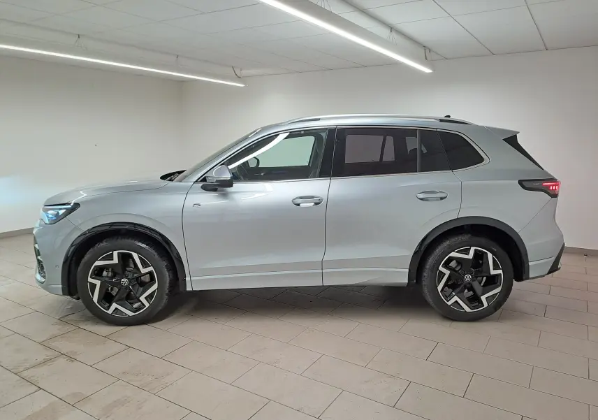 Volkswagen Tiguan 2.0 TDI R-Line argent Dolomite vu de profil côté gauche, avec jantes noires et vitres surteintées.