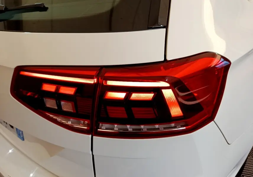 Gros plan sur les feux arrière allumés côté droit d'une Volkswagen Passat blanche hybride rechargeable.