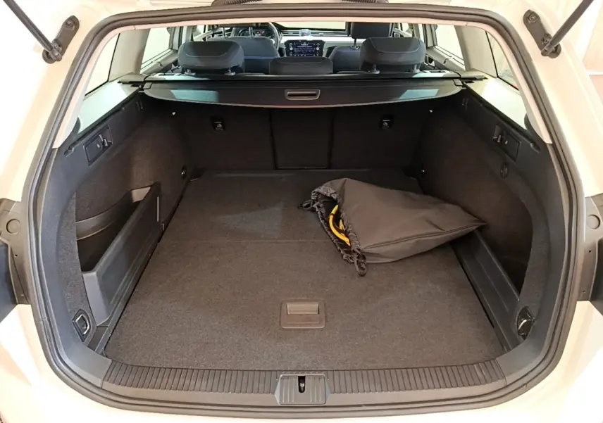 Coffre ouvert d’une Volkswagen Passat blanche hybride rechargeable, vue arrière montrant un espace de chargement spacieux avec un sac noir.