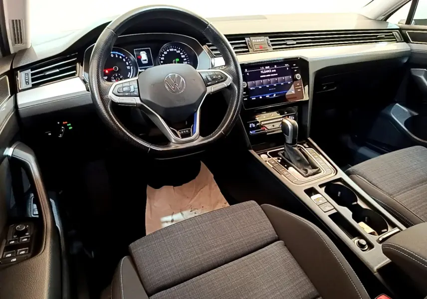 Vue intérieure de la Volkswagen Passat GTE 2021, tableau de bord et volant cuir noir avec écran tactile central.