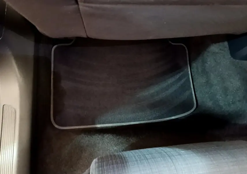 Tapis de sol noir sous le siège passager arrière d'une Volkswagen Passat blanche, vue intérieure au sol.