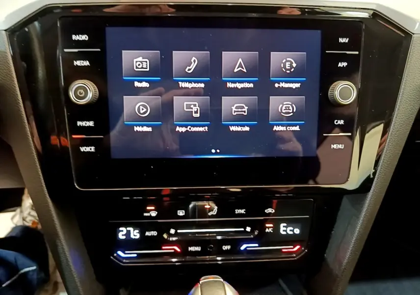 Vue rapprochée de l'écran tactile central et de la console de climatisation d'une Volkswagen Passat blanche hybride rechargeable.