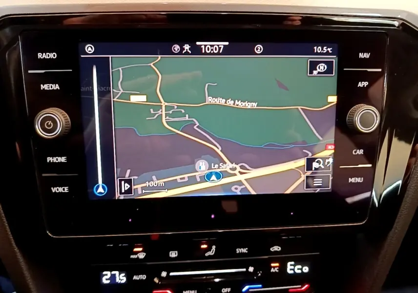 Vue rapprochée de l'écran tactile central du système de navigation d'une Volkswagen Passat blanche, affichant une carte routière.