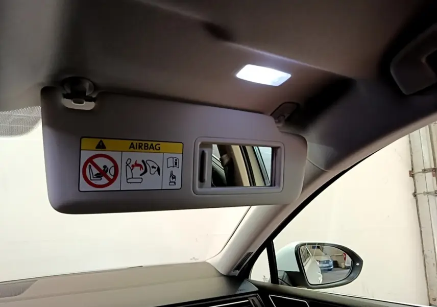 Intérieur de la Volkswagen Passat hybride 2021, vue côté passager avec pare-soleil abaissé et miroir éclairé.
