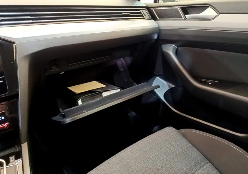 Intérieur de Volkswagen Passat hybride 2021, vue côté passager sur boîte à gants ouverte et siège tissu gris.