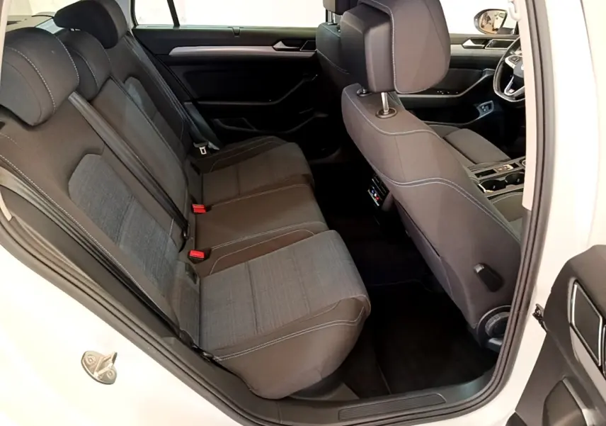 Vue intérieure côté droit montrant les sièges arrière gris foncé et la porte ouverte d'une Volkswagen Passat blanche hybride rechargeable.