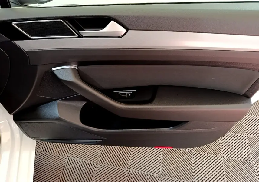 Vue rapprochée de la porte avant gauche blanche d'une Volkswagen Passat GTE 2021 avec poignée et commande de verrouillage.