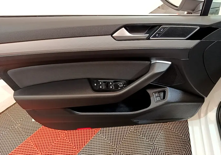 Vue latérale du panneau de porte avant gauche noir avec commandes électriques sur Volkswagen Passat blanche hybride rechargeable 2021.