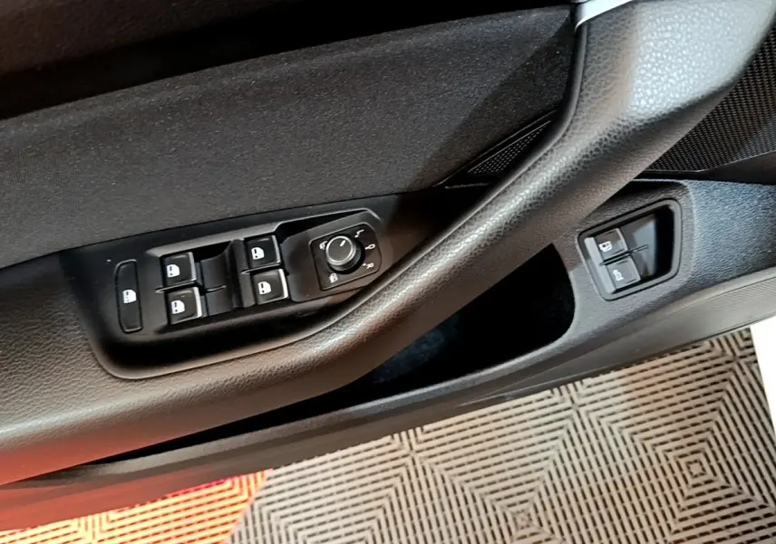 Gros plan sur la commande des vitres et rétroviseurs côté conducteur de la Volkswagen Passat blanche hybride rechargeable.