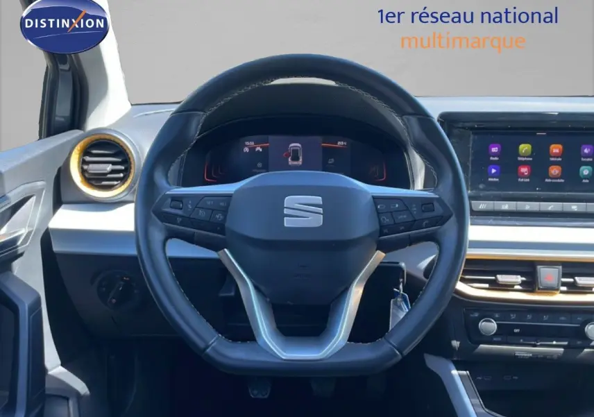 Vue intérieure centrée sur le volant noir du SEAT Arona 2025 avec tableau de bord digital et écran tactile.