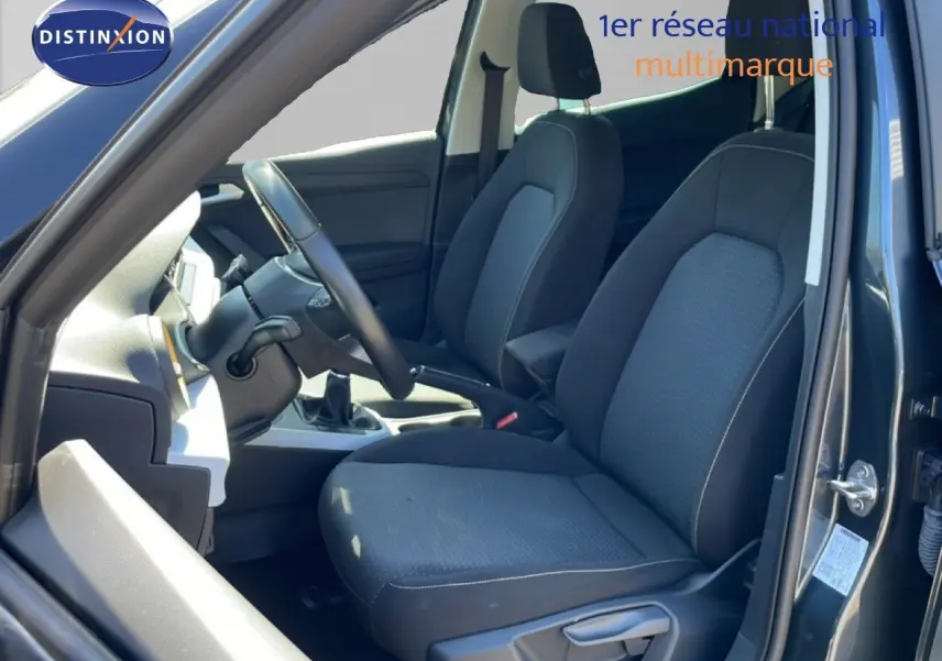 Vue intérieure côté conducteur du SEAT Arona 2025, montrant les sièges tissu noirs et le volant multifonction.