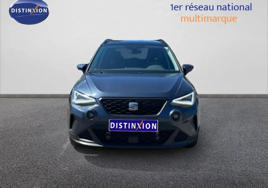 Vue avant d'un SEAT Arona gris Magnetic Metal avec toit noir, phares LED allumés sur fond neutre.