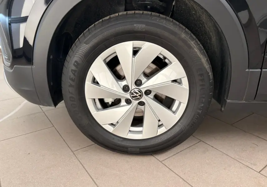 Gros plan sur la roue avant gauche du Volkswagen T-cross noir intense 2024 avec jante argentée et pneu Goodyear.