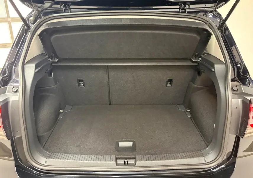 Coffre ouvert vu de l'arrière d'un Volkswagen T-Cross noir intense 2024, intérieur spacieux et bien fini.