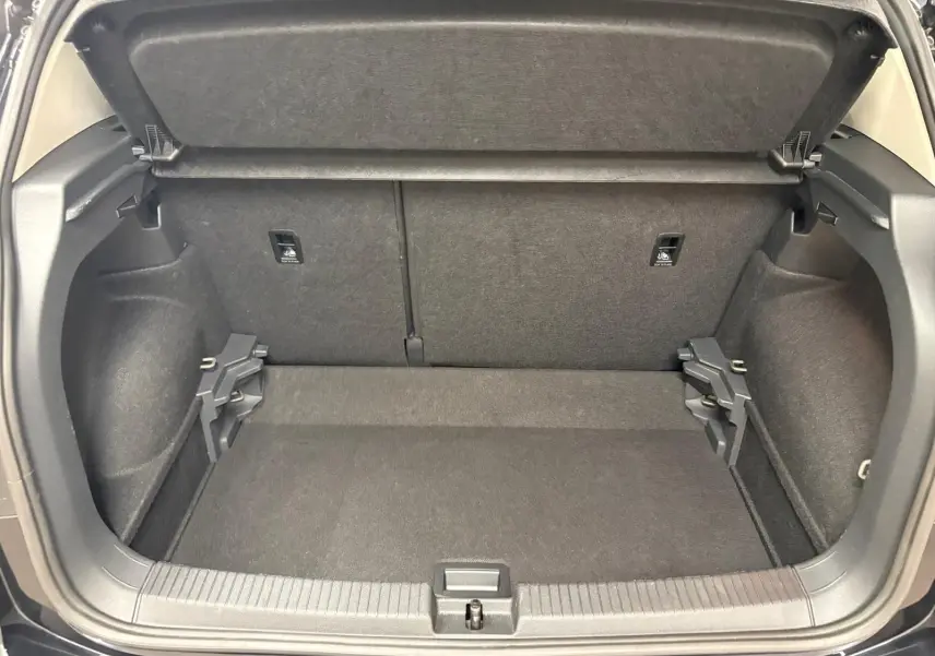 Coffre ouvert du Volkswagen T-Cross noir intense 2024, vue arrière montrant l'espace de chargement vide et la tablette cache-bagages relevée.