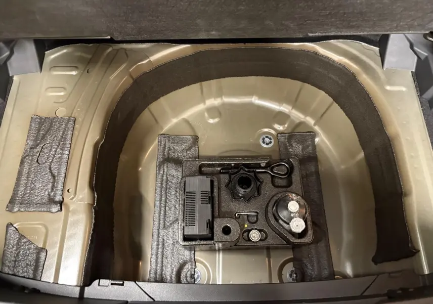 Coffre ouvert du Volkswagen T-cross noir intense 2024, montrant le rangement sous plancher avec outils intégrés.