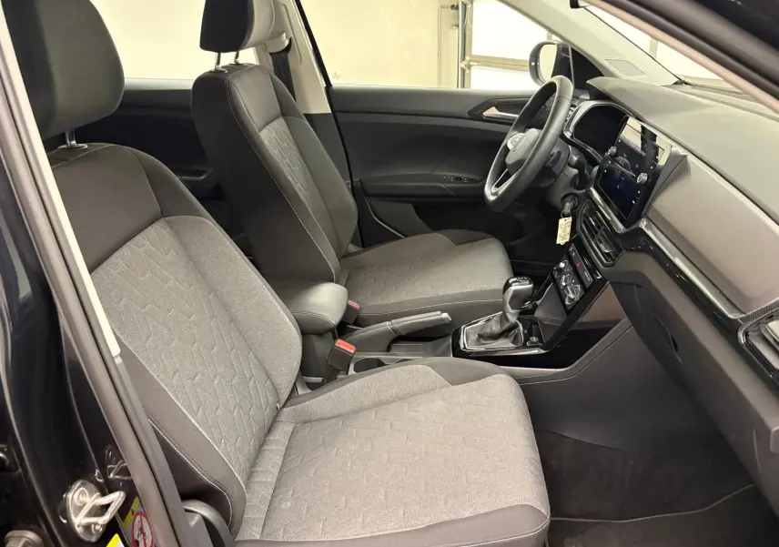Vue intérieure côté conducteur du Volkswagen T-Cross 2024 avec sièges gris et tableau de bord moderne.