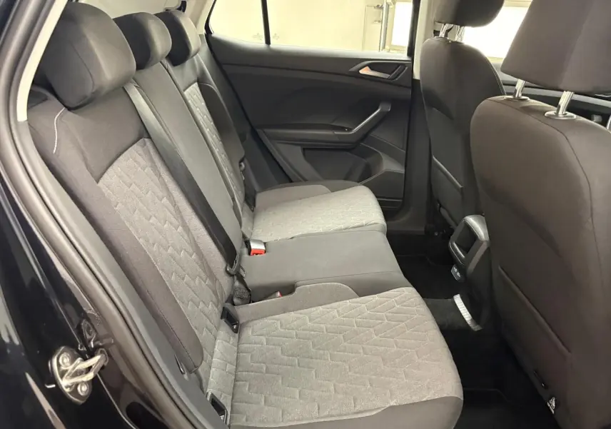 Vue intérieure arrière côté gauche du Volkswagen T-Cross 2024 noir intense, montrant les sièges arrière en tissu gris et noir.