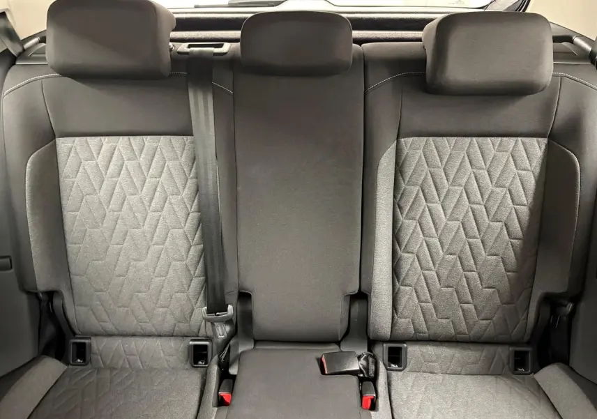 Vue intérieure arrière des sièges arrière du Volkswagen T-Cross 2024 avec tissu gris à motifs géométriques et appuie-têtes noirs.