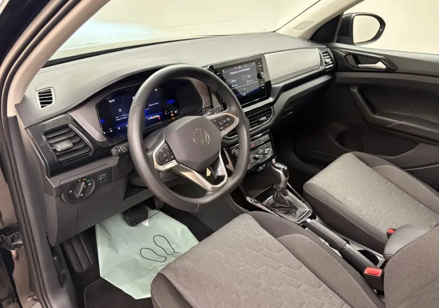 Intérieur du Volkswagen T-Cross 2024 vu côté conducteur, tableau de bord moderne avec écran tactile et sièges gris.