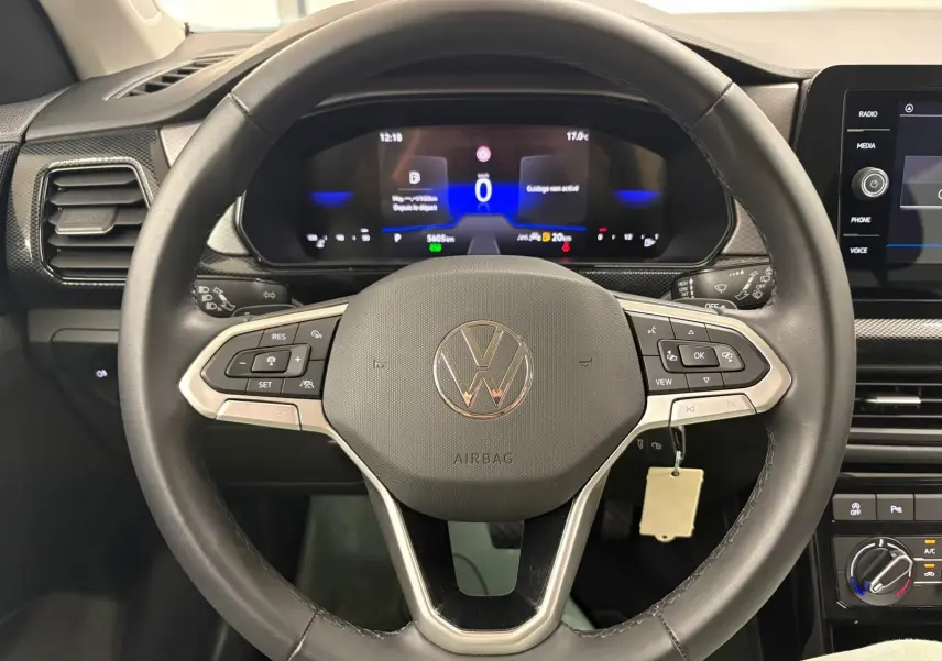 Vue rapprochée du volant noir du Volkswagen T-Cross 2024 avec tableau de bord numérique et commandes intégrées.