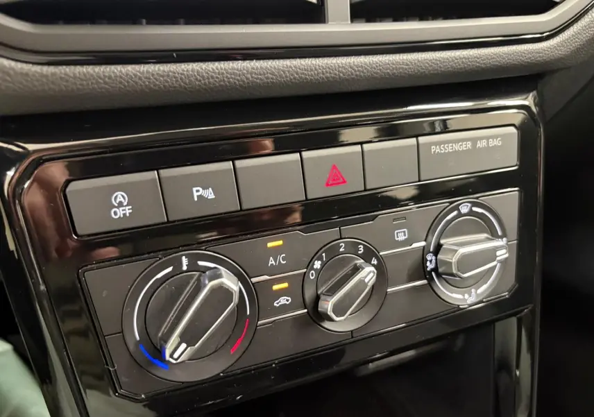 Gros plan sur les commandes de climatisation et sécurité du tableau de bord noir du Volkswagen T-Cross 2024.