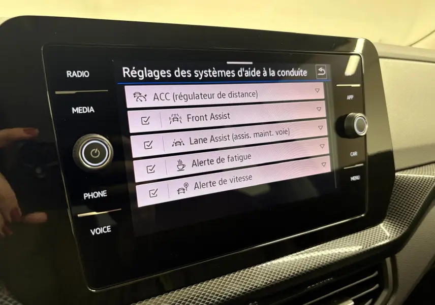 Écran tactile central du Volkswagen T-Cross 2024 affichant les réglages des aides à la conduite dans un intérieur clair.