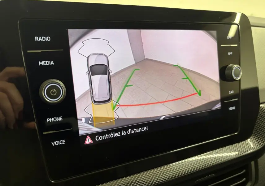 Écran multimédia du Volkswagen T-cross 2024 montrant l'aide au stationnement avec vue arrière et lignes de guidage colorées.