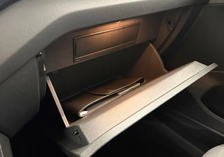 Gant de boîte à gants ouvert dans l'habitacle noir du Volkswagen T-Cross 2024, version Life Plus.