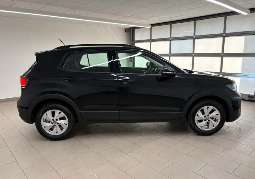 Profil côté droit du Volkswagen T-Cross 2024 noir intense avec jantes alliage dans un garage lumineux.